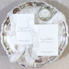 the wedding stationery is laid out on a silver platter with a white candle