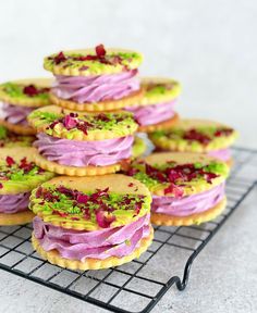 there are many cookies with different toppings on the cooling rack, all stacked up