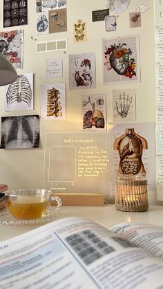 an open book sitting on top of a desk next to a cup of tea and lamp