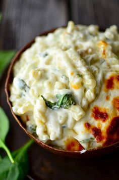 a bowl filled with macaroni and cheese on top of a wooden table