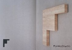 the corner of a room with a wooden shelf on it's wall and a sign that says formastudio