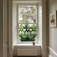 a window in a white room with green plants on the windowsill and wood flooring