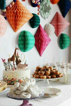 a table topped with cakes and desserts next to wall hanging paper or honeycombs