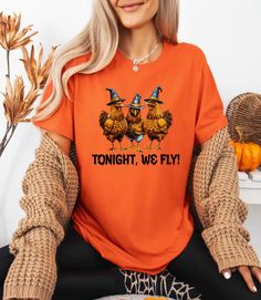 Chicken Witches Funny Halloween T-Shirt, Halloween Chicken Tonight We Fly Shirt, Vintage Chicken Witch Shirt, Funny Chicken Halloween Shirt **Product Overview   We proudly offer shirts from the Bella Canvas and Gildan SoftStyle collections, both recognized for their superior industry standards. *Bella Canvas:*   - Available in unisex sizing   - Lightweight fabric at 4.2 oz   - Solid colors are crafted from 100% Combed and Ring-Spun Cotton   - Athletic Heather contains 90% Combed and Ring-Spun Co Spooky Orange Crew Neck Top, Funny Orange Tops For Fall, Funny Orange Top For Fall, Orange Crew Neck Top For Halloween, Halloween Funny Print Orange T-shirt, Orange Halloween T-shirt With Funny Print, Halloween Orange Crew Neck T-shirt, Funny Orange Halloween T-shirt, Orange Funny Print T-shirt For Halloween