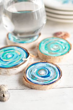 three coasters with blue swirl designs on them next to shells and seashells