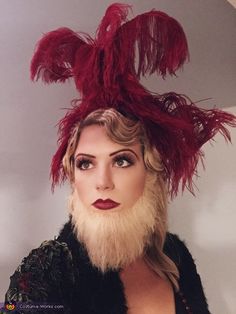 a woman wearing a red feathered hat with feathers on it's head and long blonde hair