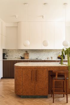 a kitchen with wooden floors and white cabinets, an island countertop and two stools