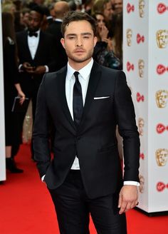 a man in a suit and tie on the red carpet at an awards event,