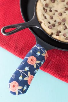 chocolate chip cookie in a cast iron skillet next to a red napkin on a blue table