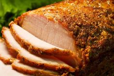 sliced ham sitting on top of a white plate with lettuce in the background