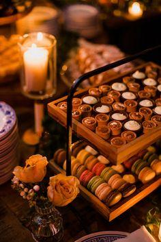 a table topped with lots of different types of pastries on trays next to candles