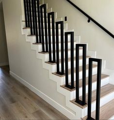 a set of stairs with black railings and wood flooring in an empty room