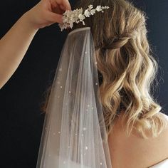 the bride is getting ready to put her wedding veil on and combed with flowers