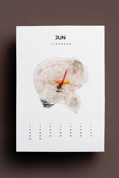 a calendar with an image of a dragonfly on it's cover, in front of a brown background