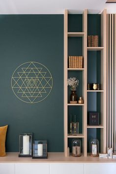 a living room with green walls and shelves filled with books, candles and vases