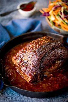 a steak in a skillet next to a bowl of coleslaw