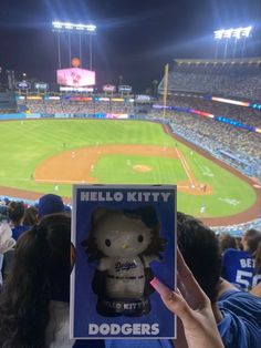 someone holding up a hello kitty bobble head at a baseball game