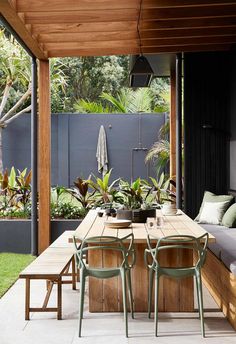 an outdoor dining area with wooden tables and chairs, surrounded by greenery in the background