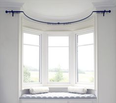 a white window seat in front of a round window with two pillows on the bench