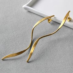 "These elongated gold ribbons are the perfect statement earrings. Light to wear with maximum visual impact these are a sublime evening earring.  With the appearance of movement even when still, these beautiful earrings will make the perfect gift. So if you're heading out with the girls or want to make waves at a wedding these earrings are ideal. Almost skimming the collar these elegant earrings are subtle yet eye catching. With fashion bloggers raving about their style and and waterfall vibe everyone will be asking \"where did you get them?\"  Whether they're a treat for you or someone special everyone will notice these dynamically different earrings." Elegant Yellow Gold Wrap Earrings For Party, Chic Gold Wrap Earrings For Formal Occasions, Modern Gold Wrap Earrings For Formal Occasions, Modern Gold Linear Earrings For Evening, Elegant Gold Wrap Earrings For Anniversary, Elegant Drop Earrings For Evening, Elegant Drop Wrap Earrings For Evening, Elegant Gold Linear Earrings For Evening, Elegant Gold Wrap Earrings For Evening