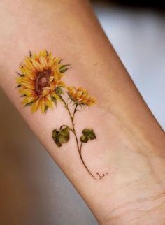 a small sunflower tattoo on the left forearm and wrist is painted with watercolors