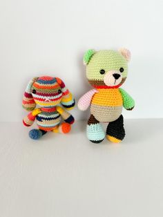 two crocheted teddy bears sitting next to each other on a white table top