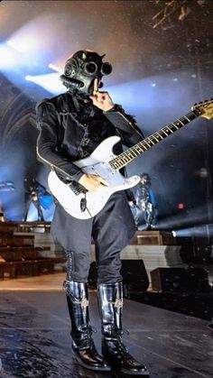 a man with a gas mask on holding a guitar