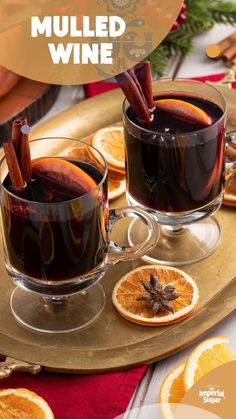 two glasses of mulled wine on a tray with orange slices and cinnamon sticks in them