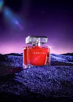 a bottle of narciss perfume sitting on top of a rocky hill under a purple sky