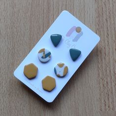 a set of four different colored and shaped buttons on a white board with wood grained surface