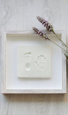 a white frame with a flower and two footprints on it