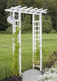 an outdoor garden with white trelliss and a clock