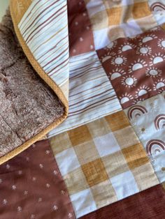 a close up of a patchwork quilt on a bed with brown and tan colors