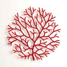 a red coral shaped object sitting on top of a white surface