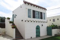 a white house with green shutters and stairs