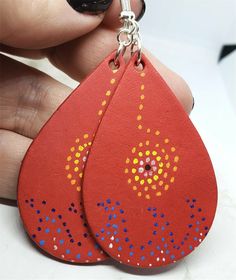 a pair of red leather earrings with blue and yellow dots on the tear shaped drop