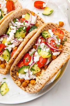 three pita breads filled with vegetables and feta cheese on a white plate