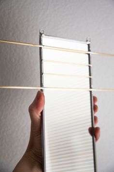 a hand is holding a piece of paper with clothes pins attached to the back of it