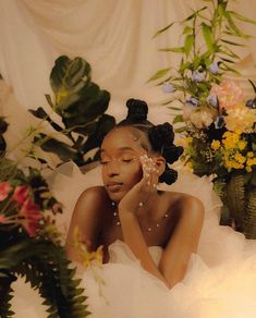 a woman sitting in front of flowers with her hand on her face