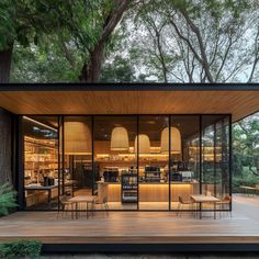 an outdoor dining area in the middle of a forest with wooden floors and large windows