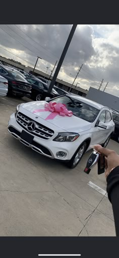 a person holding a remote control in front of a car with a pink bow on it