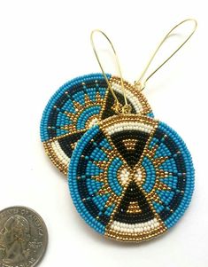 two blue and white beaded earrings next to a penny on a white surface with a coin in the foreground