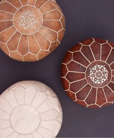 three decorative round poufles sitting on top of a purple surface with white stitching