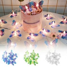 there is a cake decorated with butterflies and fairy lights on the table next to it