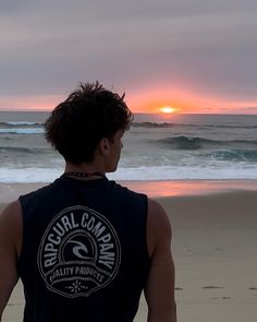 a man standing on top of a beach next to the ocean