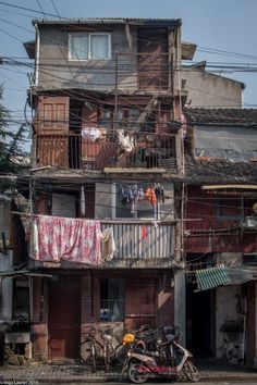 two bicycles parked in front of an old building with clothes hanging on the balconys