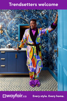 a man standing in front of a blue door wearing a colorful robe and purple shoes