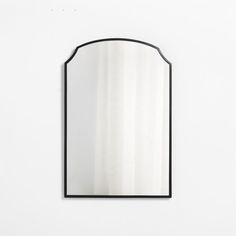 a mirror that is on the wall with a black frame and white curtain behind it