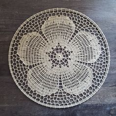 a white doily is sitting on a wooden table with a black surface behind it