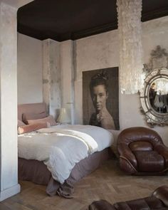 a bedroom with a bed, chair and pictures on the wall in it's corner